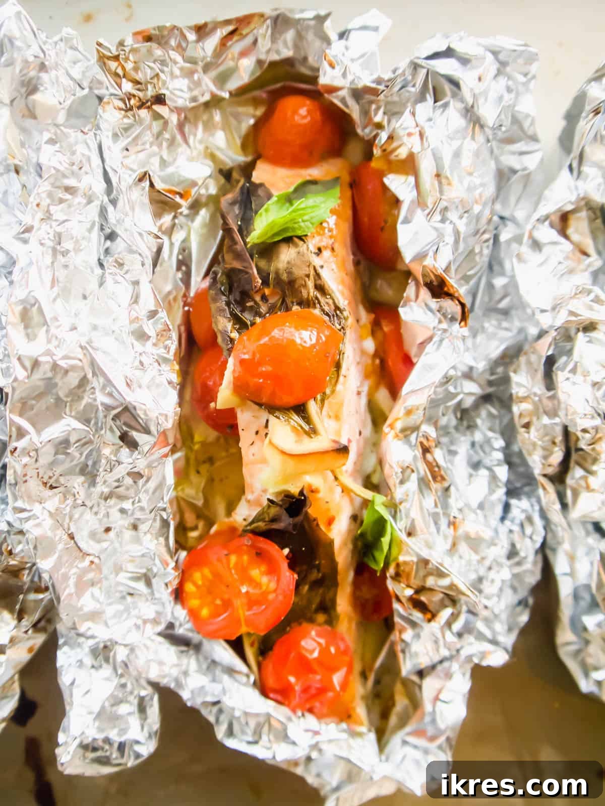 Basil Tomato Salmon Foil Packets 8 Oven baked salmon foil packets cooking in the oven.