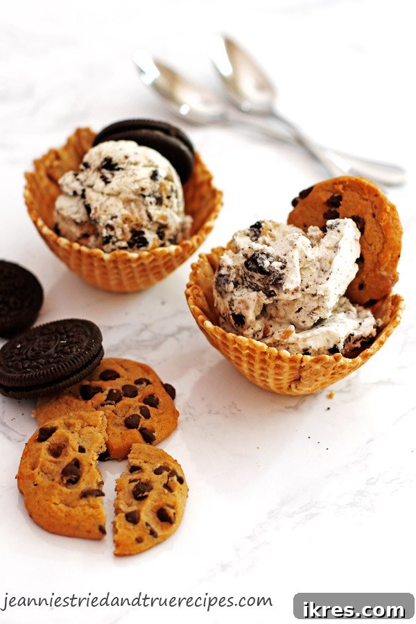 Monster Cookie Dough Dream 2 Two waffle cones filled with vibrant blue Cookie Monster ice cream, adorned with extra chocolate chip and chocolate sandwich cookies, against a bright background.