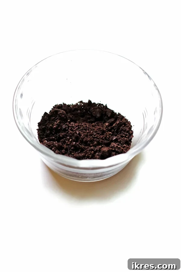 Monster Cookie Dough Dream 5 A small Pyrex bowl containing finely crushed chocolate sandwich cookies, resembling dark, fine crumbs.