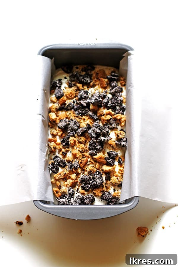 Monster Cookie Dough Dream 6 A loaf pan with layers of blue ice cream mixture and coarsely crushed cookies, ready for freezing.