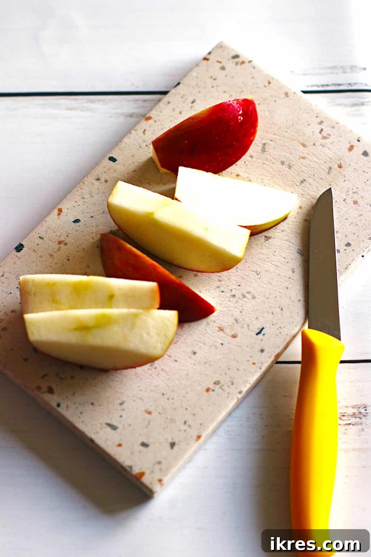 Berry Orchard Smoothie 4 Fresh apple sliced into medium pieces on a wooden cutting board, with a knife resting nearby.