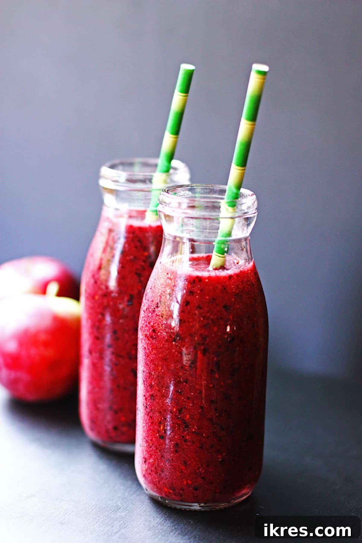 Berry Orchard Smoothie 7 Two jars of refreshing apple berry smoothie, each with a green straw, on a white table.