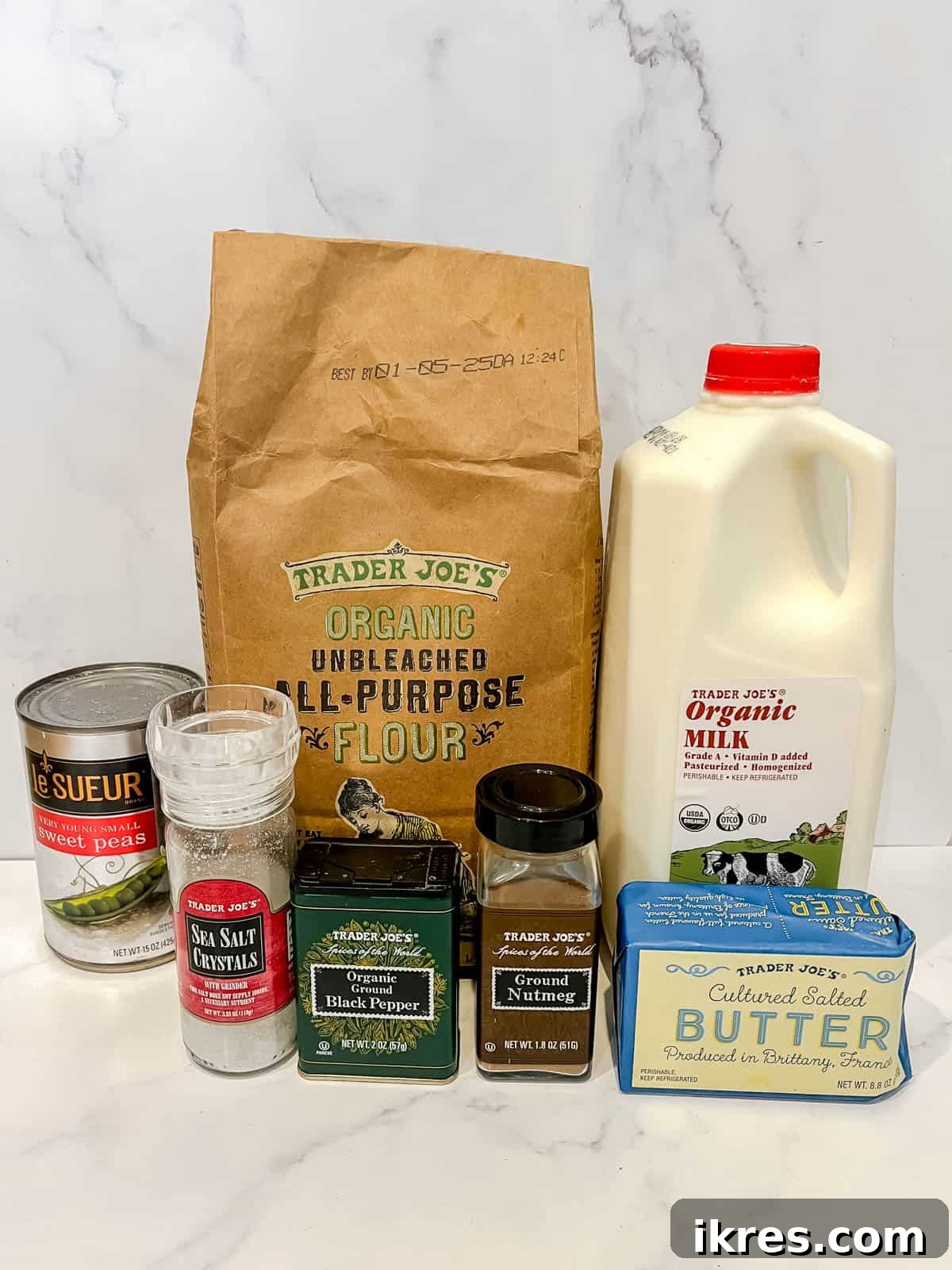 A flat lay of all the ingredients required to make creamed peas, including butter, flour, milk, peas, and spices.