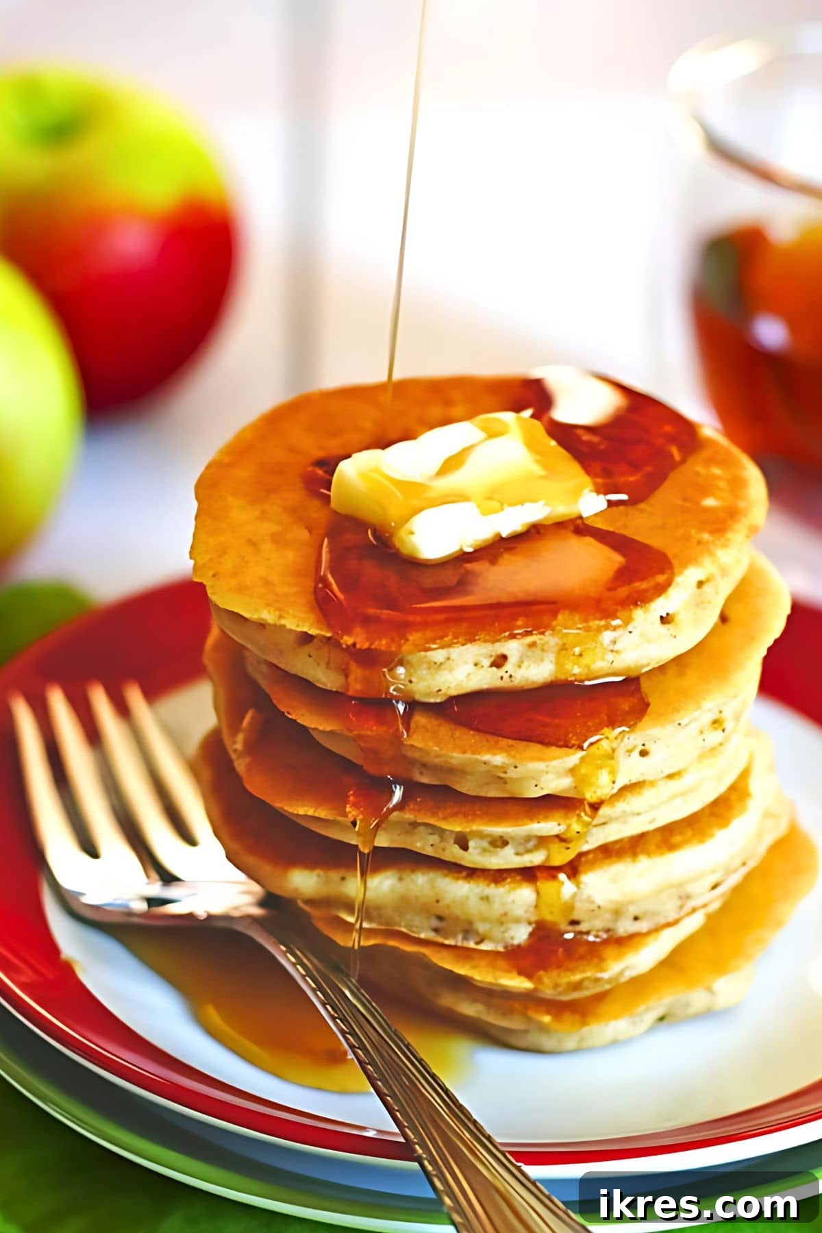 Golden Apple Cinnamon Flapjacks 2 A stack of fluffy Apple Cinnamon Pancakes on a plate, topped with melted butter and maple syrup.