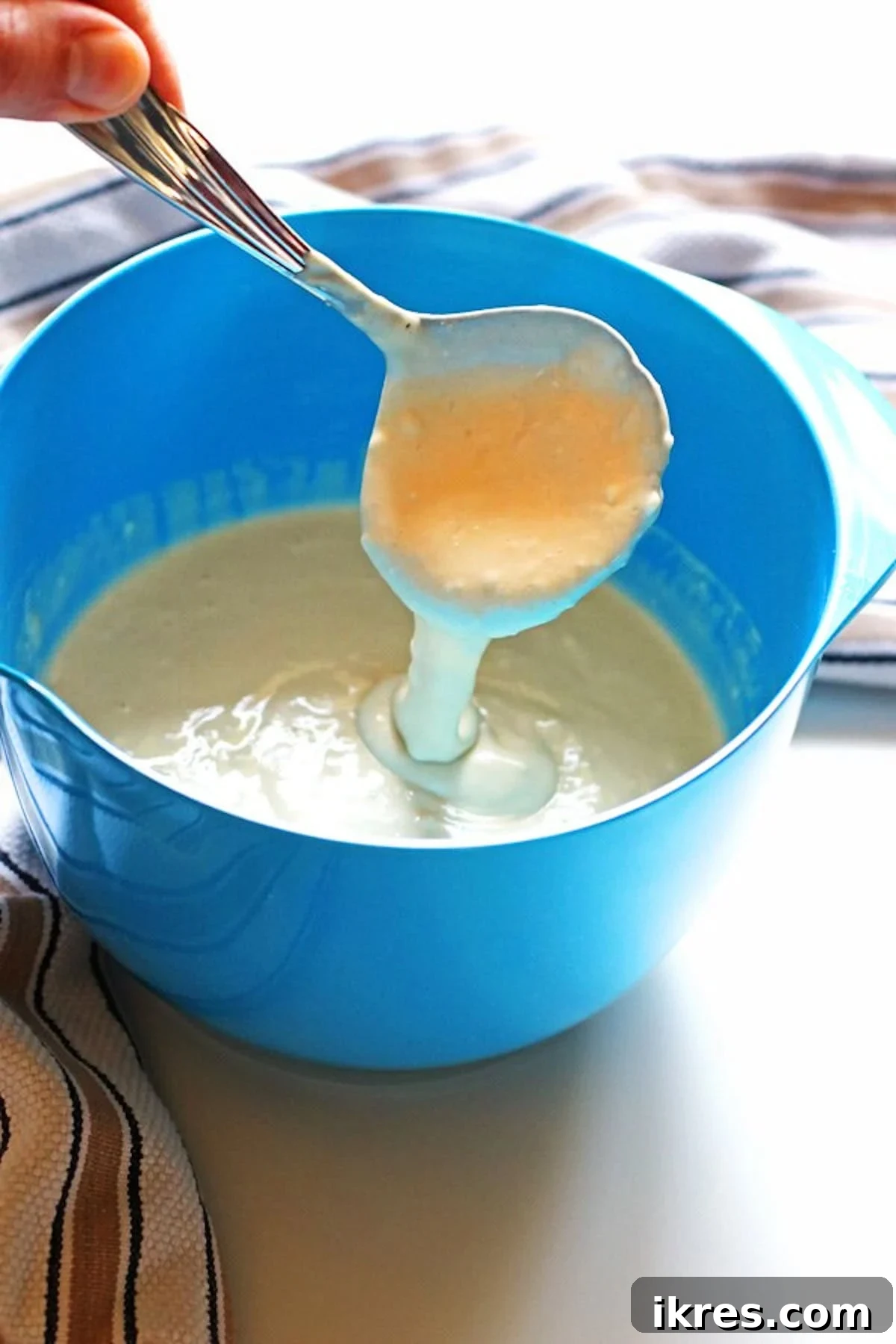 Golden Apple Cinnamon Flapjacks 4 Pancake batter in a blue mixing bowl with a ladle scooping out the batter, ready for the griddle.