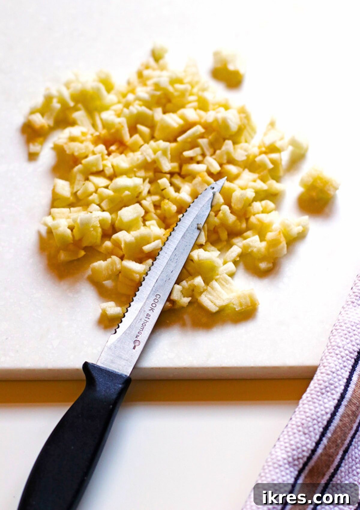 Golden Apple Cinnamon Flapjacks 5 Finely diced apples on a wooden cutting board, ready to be added to the pancake batter.
