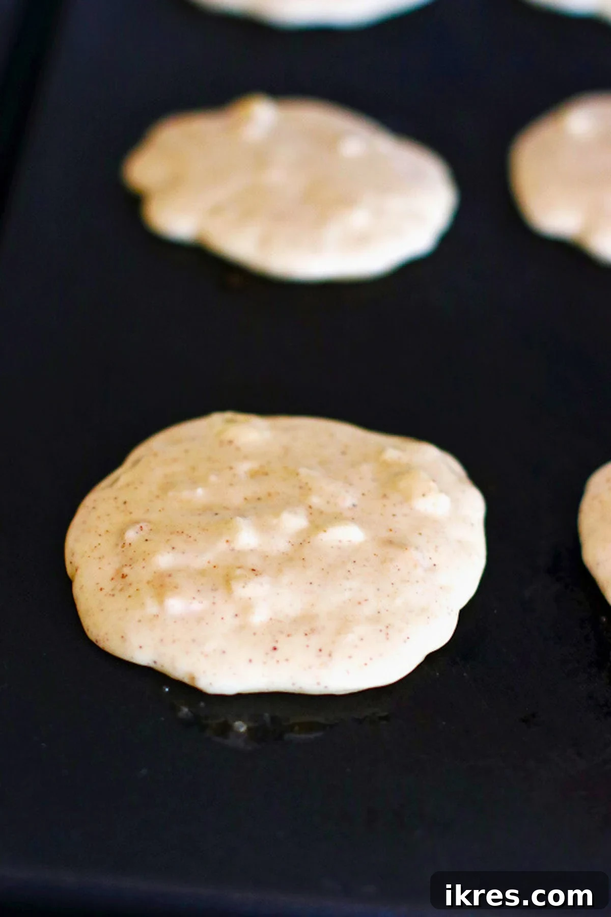 Golden Apple Cinnamon Flapjacks 6 Pancake batter cooking on a heated griddle, forming golden-brown pancakes.