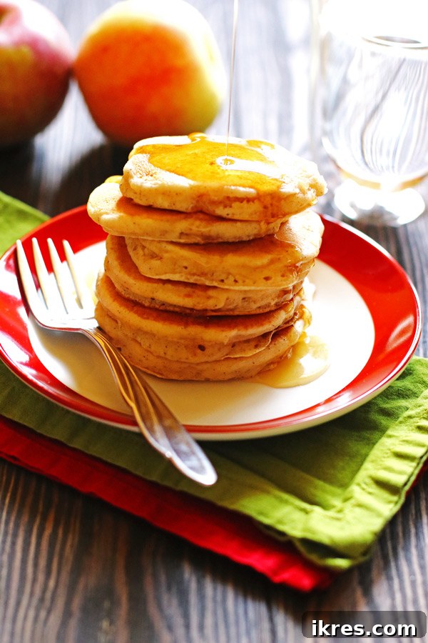 Golden Apple Cinnamon Flapjacks 7 A plate of freshly cooked Apple Cinnamon Pancakes, drizzled with syrup and topped with a pat of butter.