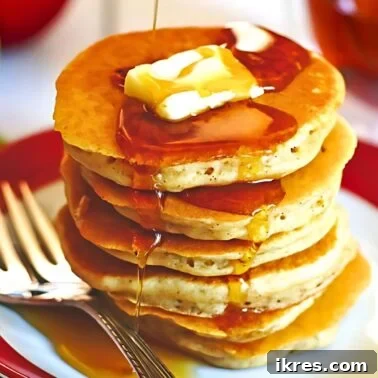 Golden Apple Cinnamon Flapjacks 8 A stack of apple cinnamon pancakes on a plate with slices of butter and maple syrup on them.