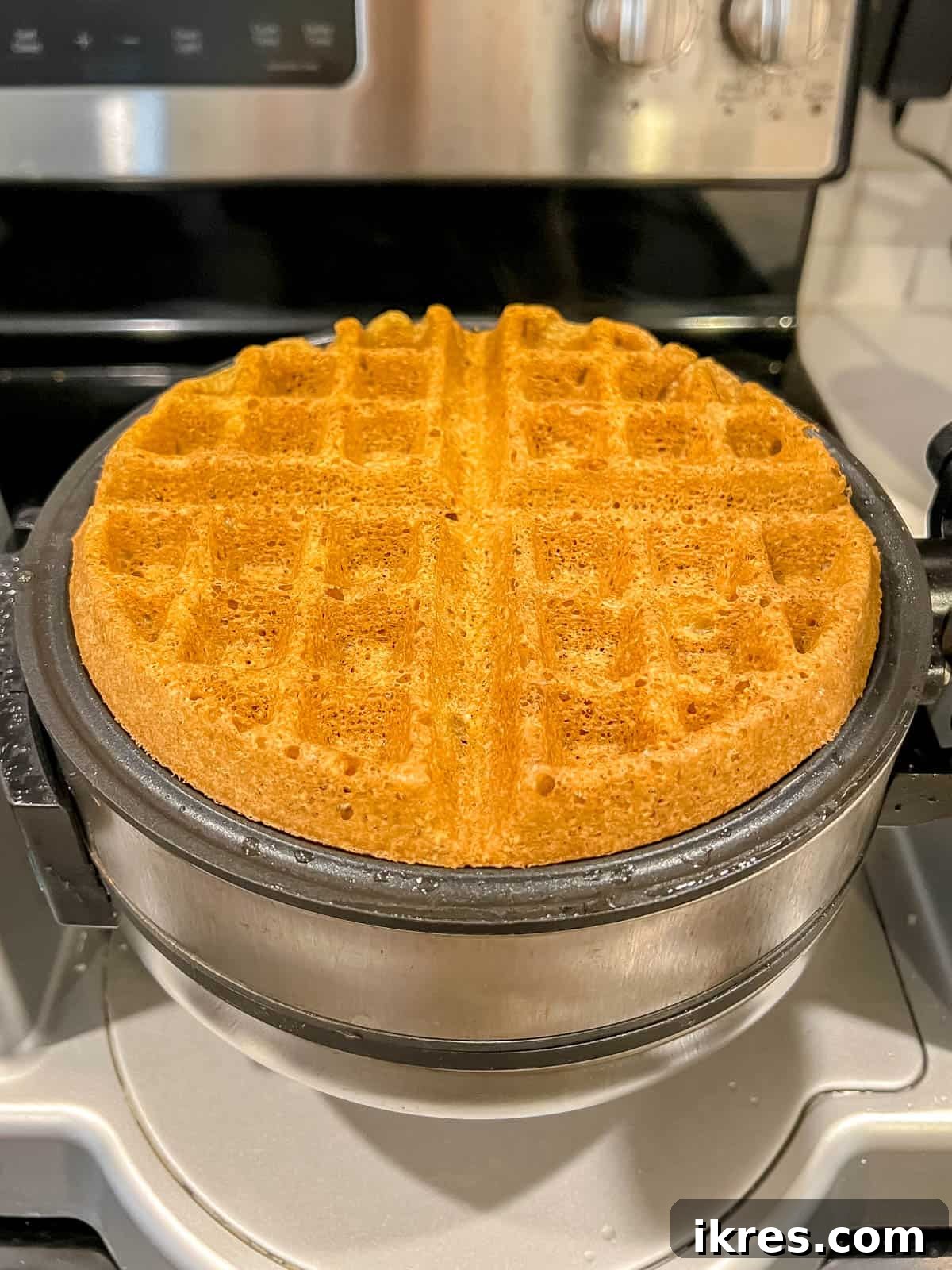 A freshly cooked Paleo waffle, golden and crispy, removed from the waffle maker.