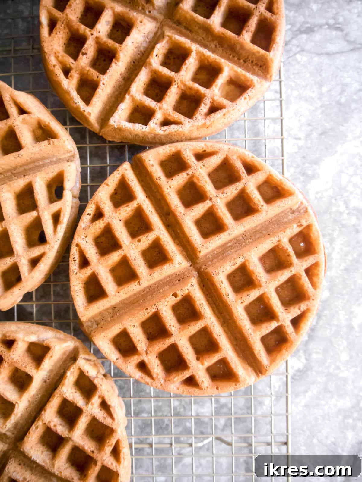 Freshly cooked Paleo Belgian waffles cooling on a wire rack to prevent sogginess.