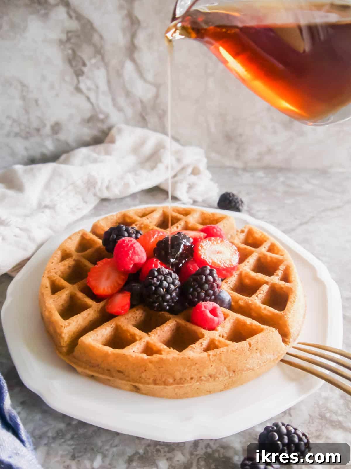 Golden Paleo Belgian waffles being generously drizzled with rich maple syrup.