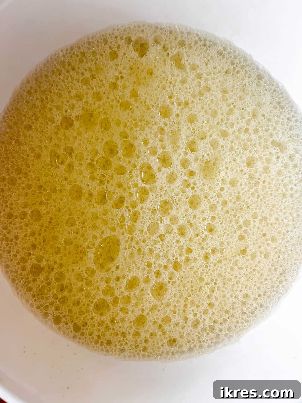 Wet ingredients for the waffle recipe, including beaten egg yolks, olive oil, almond milk, and vanilla extract, mixed in a separate bowl.
