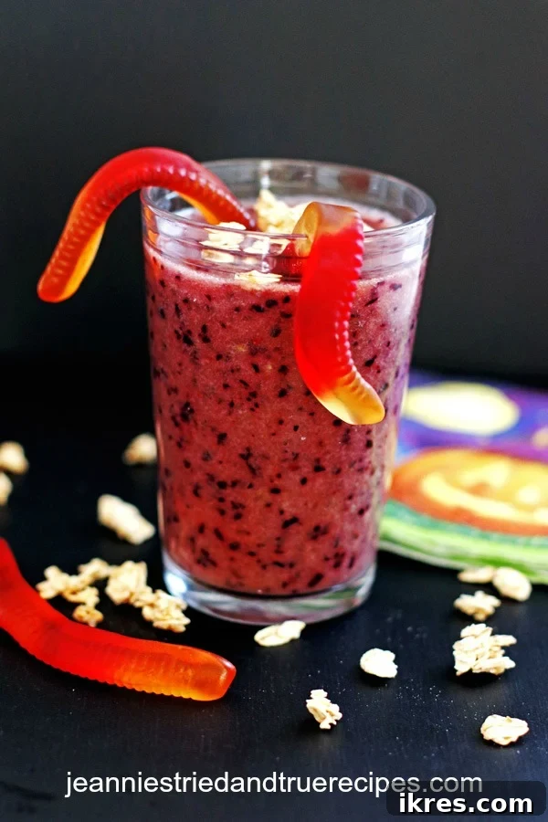 The Ultimate Purple Powerhouse 2 Vibrant purple smoothie in a clear glass, garnished with playful gummy worms and a sprinkle of granola, set against a festive Halloween backdrop.