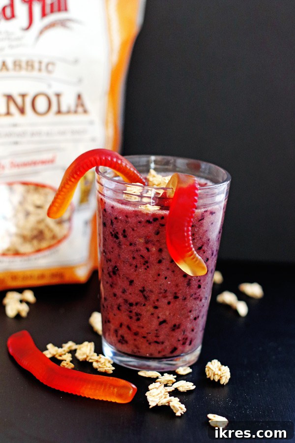 The Ultimate Purple Powerhouse 5 Close-up of the Purple People Eater Smoothie, showcasing its vibrant color and the fun addition of gummy worms and a sprinkling of granola for texture.