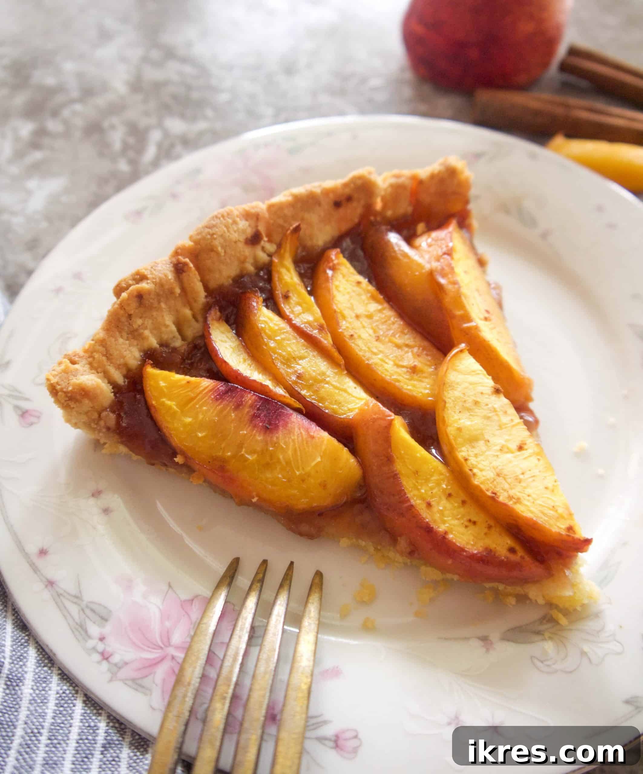 A perfectly sliced piece of gluten-free nectarine tart on a white plate, highlighting its flaky crust and juicy fruit filling.