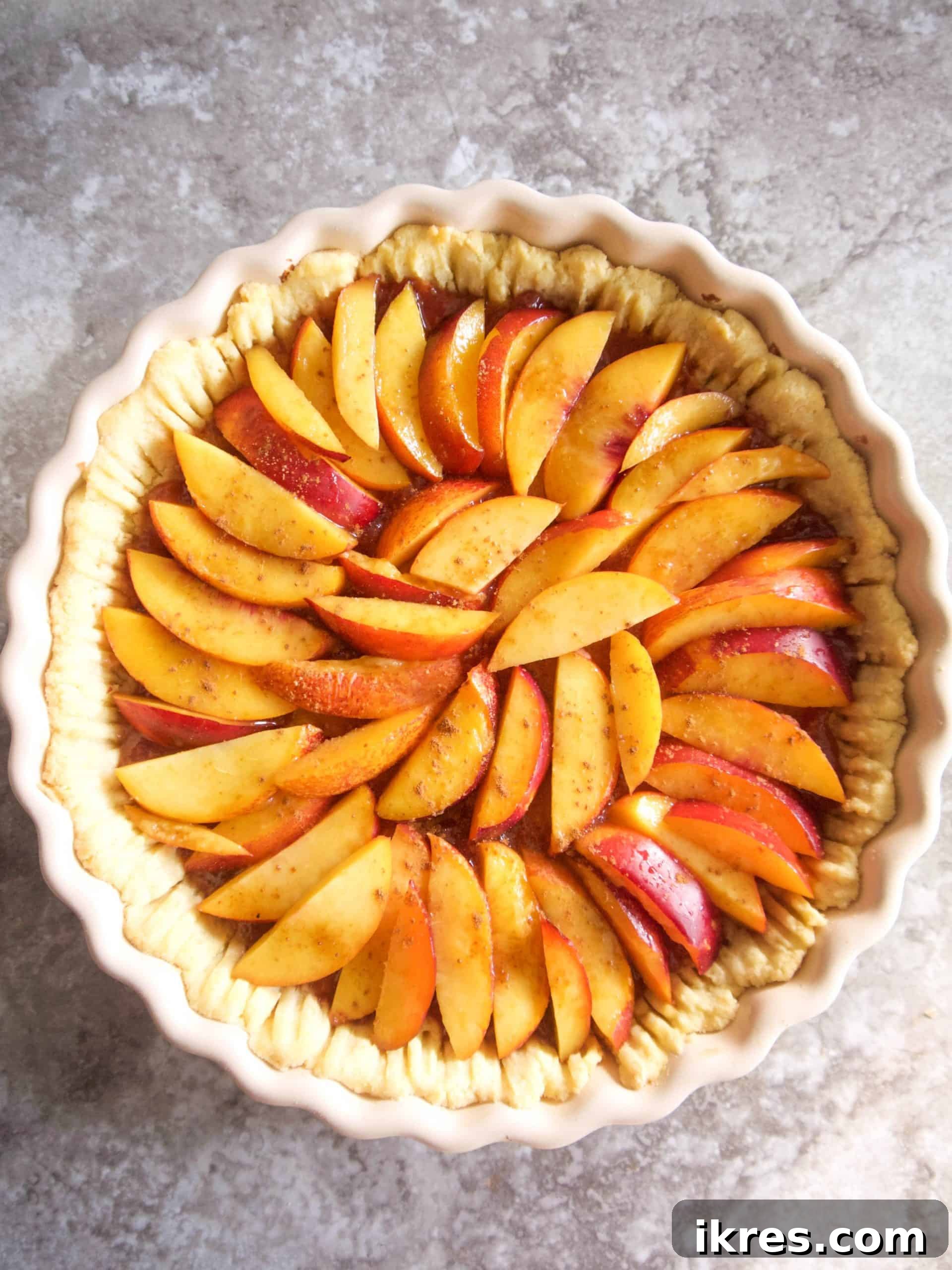 Nectarine tart beautifully arranged with sliced nectarines in a circular pattern, prior to final baking.