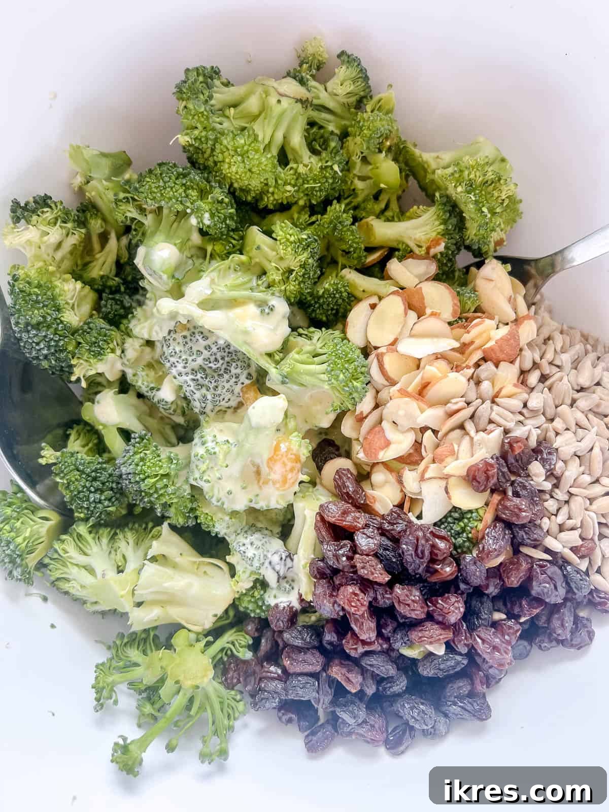 The creamy dressing being poured over the dry salad ingredients.