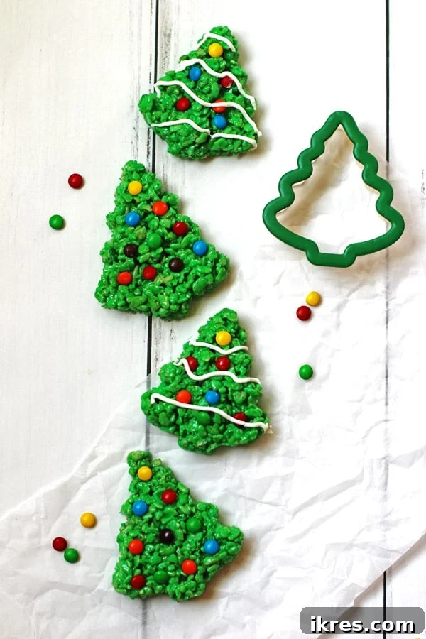A festive arrangement of green Christmas Rice Krispie trees, beautifully decorated with colorful M&M candies and a delicate drizzle of white icing.
