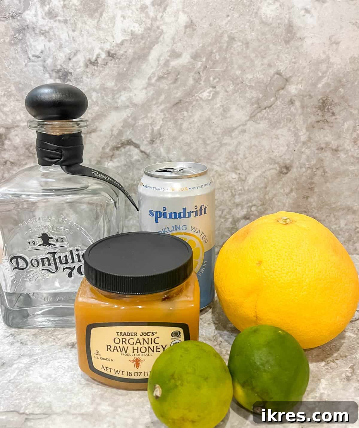 Naturally Sweet Honey Paloma 3 All the fresh ingredients laid out on a table, including grapefruits, limes, honey, tequila, and sparkling water, ready for making a homemade paloma cocktail.