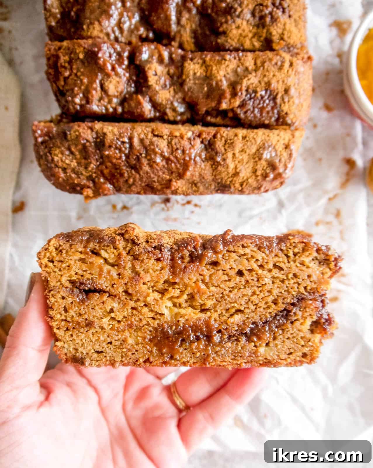 Wholesome Paleo Cinnamon Swirl Pumpkin Banana Bread 7 Someone holding a slice of Paleo pumpkin banana bread, showcasing its delicious texture and inviting appearance.