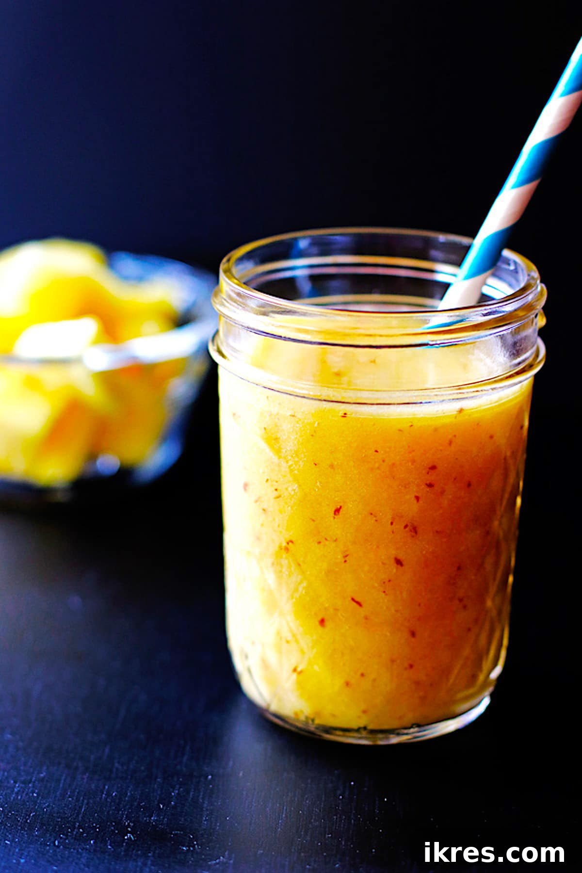 A beautifully presented tropical smoothie in a mason jar, complete with a vibrant blue straw, evoking a sense of refreshment and relaxation.