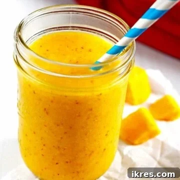 A creamy smoothie made from pineapple, mango and banana in a canning jar, garnished for freshness.