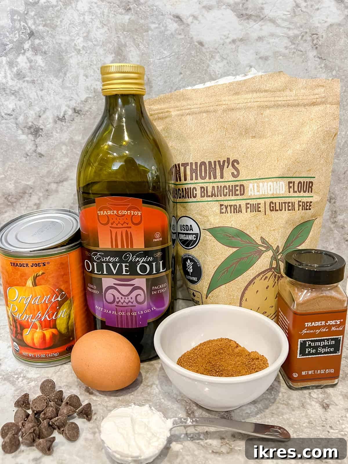 Easy Paleo Pumpkin Spice Mug Cake 4 Individual ingredients for a pumpkin mug cake, including coconut sugar, olive oil, pumpkin puree, an egg yolk, almond flour, tapioca flour, pumpkin pie spice, and chocolate chips.
