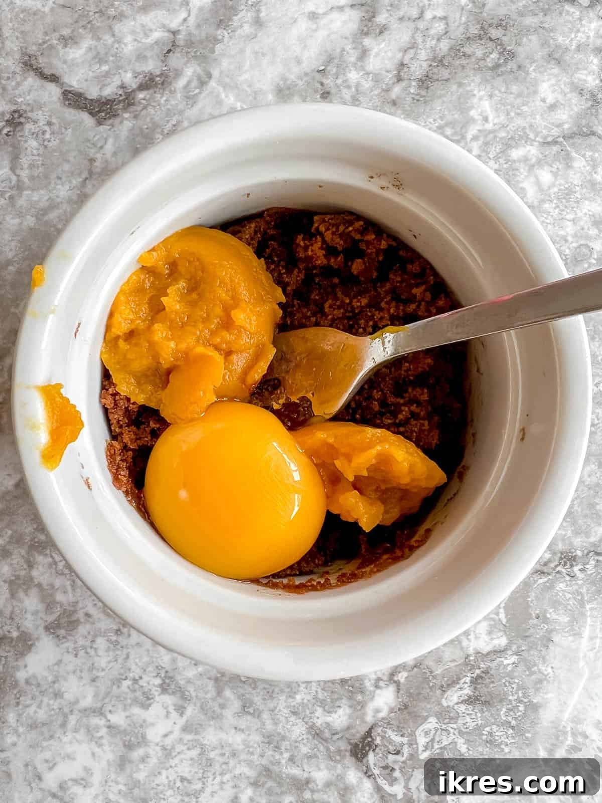 Easy Paleo Pumpkin Spice Mug Cake 6 Pumpkin puree and an egg yolk added to the sugar and oil mixture in a ramekin.