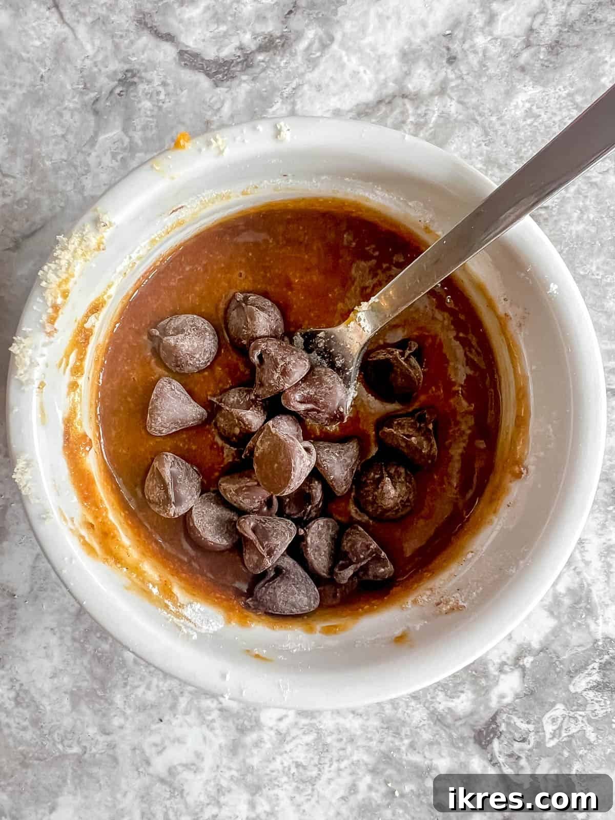 Easy Paleo Pumpkin Spice Mug Cake 8 Mini chocolate chips being stirred into the pumpkin mug cake batter in a ramekin.