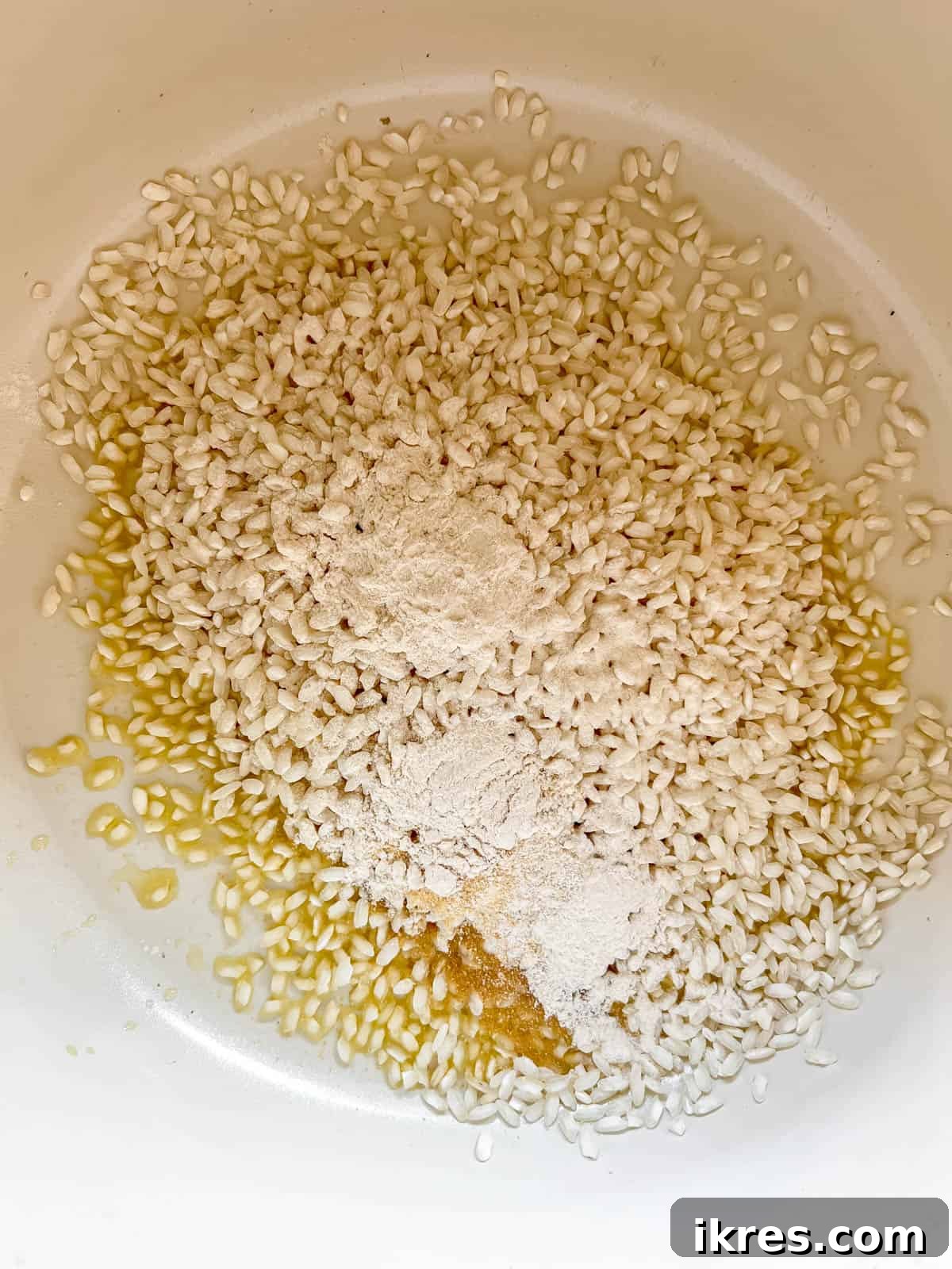 Arborio rice, garlic powder, and onion powder cooking in a pot with olive oil, beginning the risotto process.