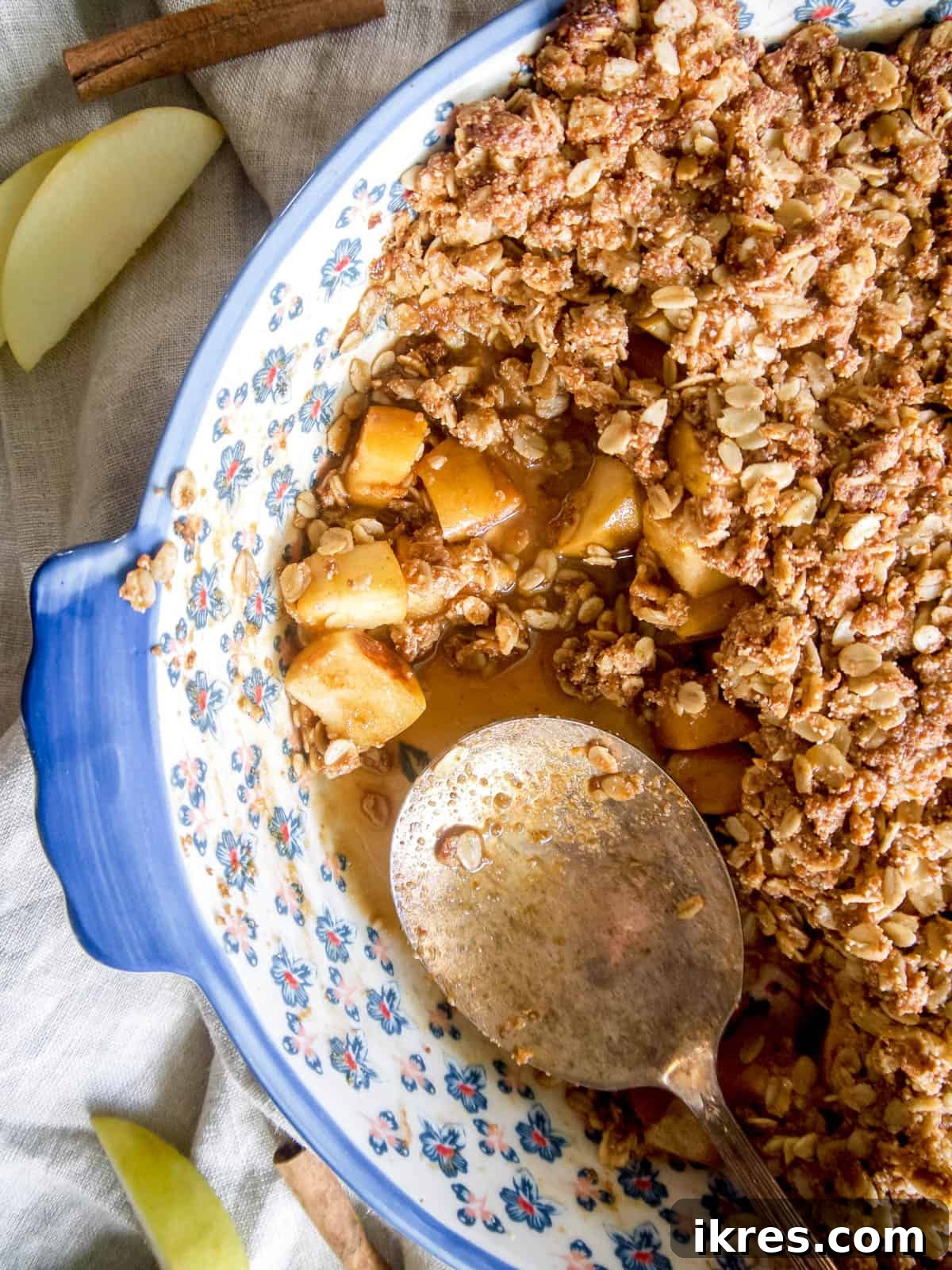 A freshly baked vegan apple crisp, served warm in a dish with a spoon.