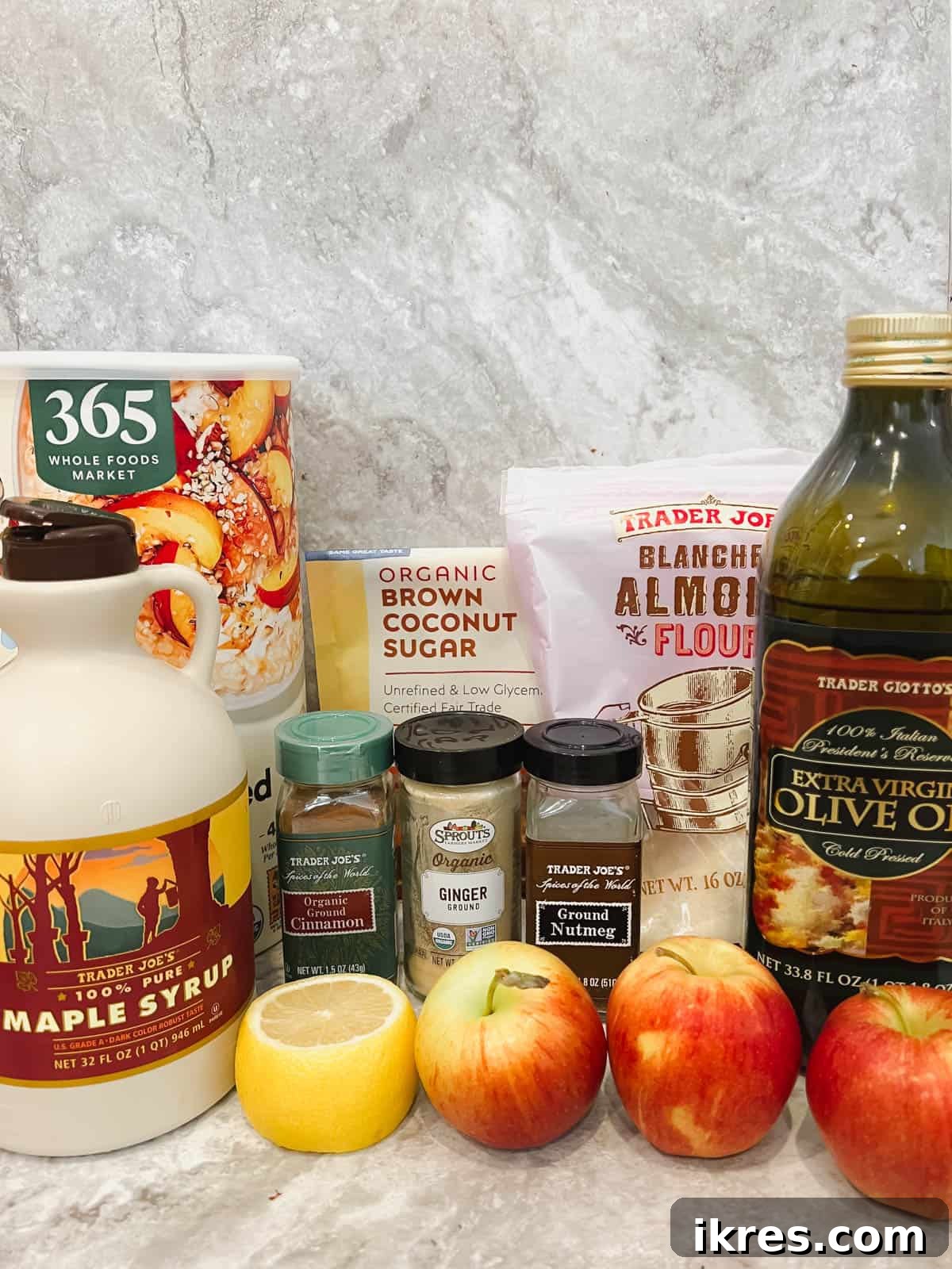 A collection of fresh ingredients, including granny smith apples, lemon, coconut sugar, almond flour, oats, and spices, laid out for making dairy-free gluten-free apple crisp.