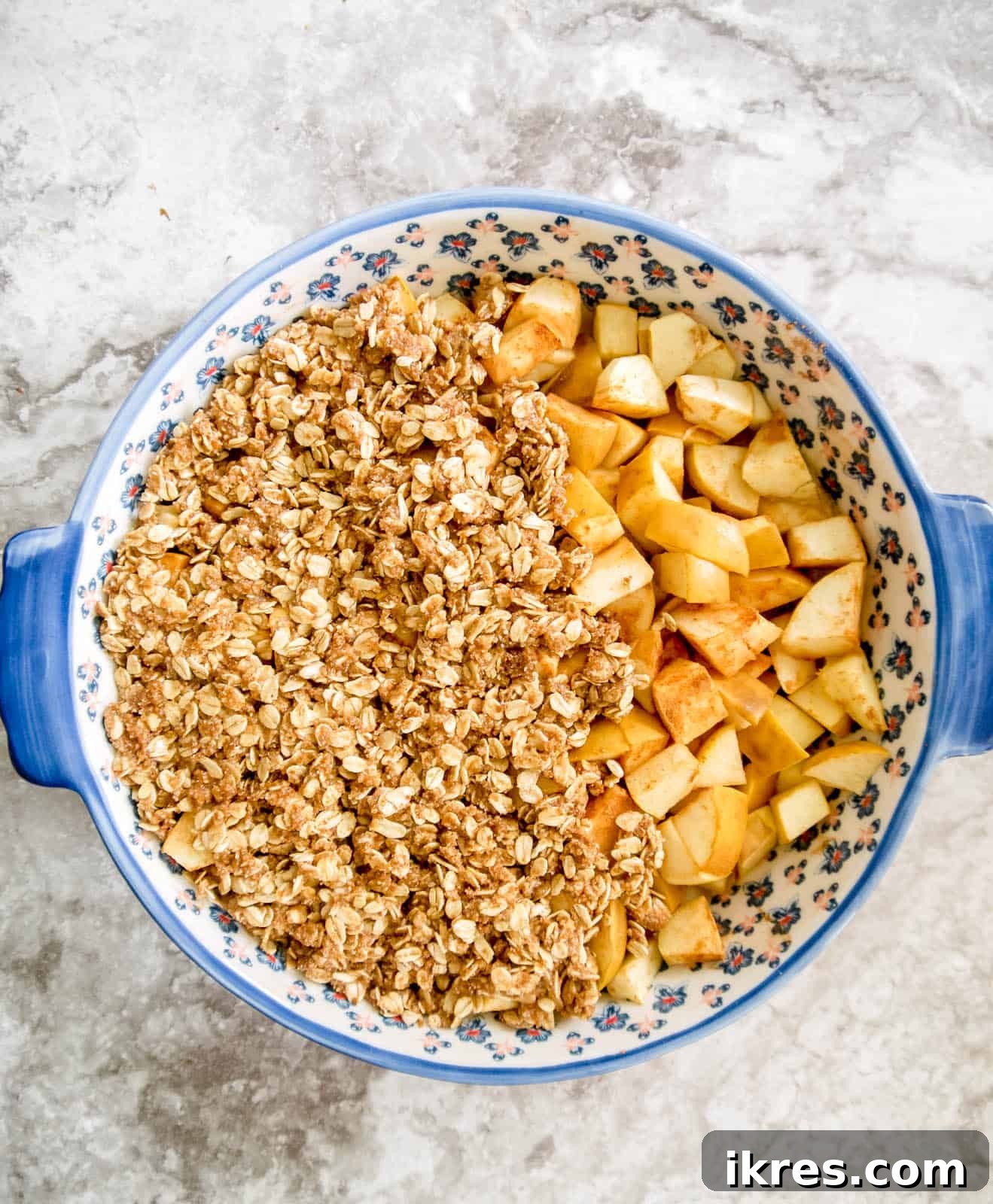 The golden-brown almond and oat topping generously covering the pre-baked apple base in a baking dish.