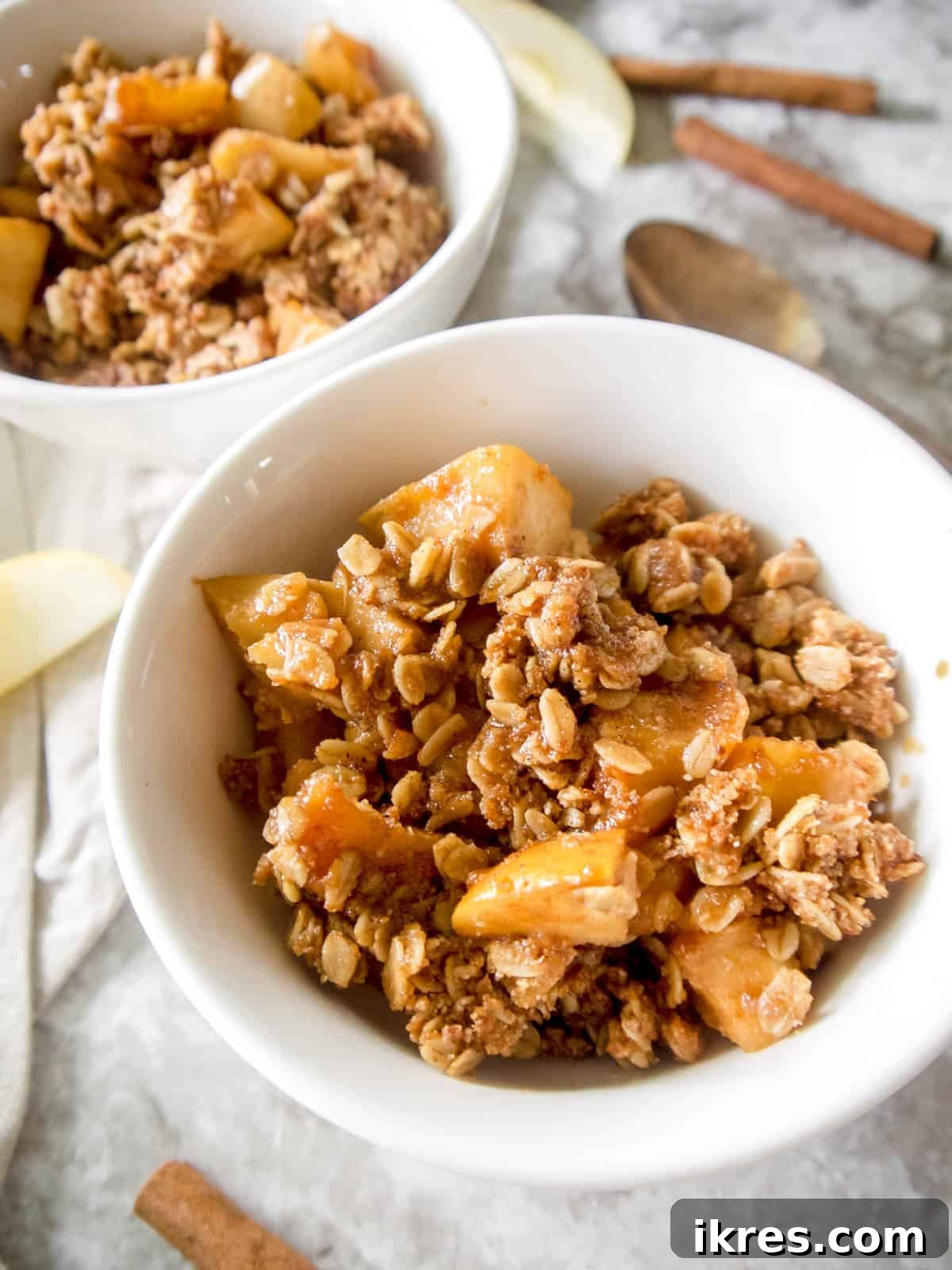 A bowl of gluten-free dairy-free apple crisp topped with a scoop of vegan ice cream, ready to eat.