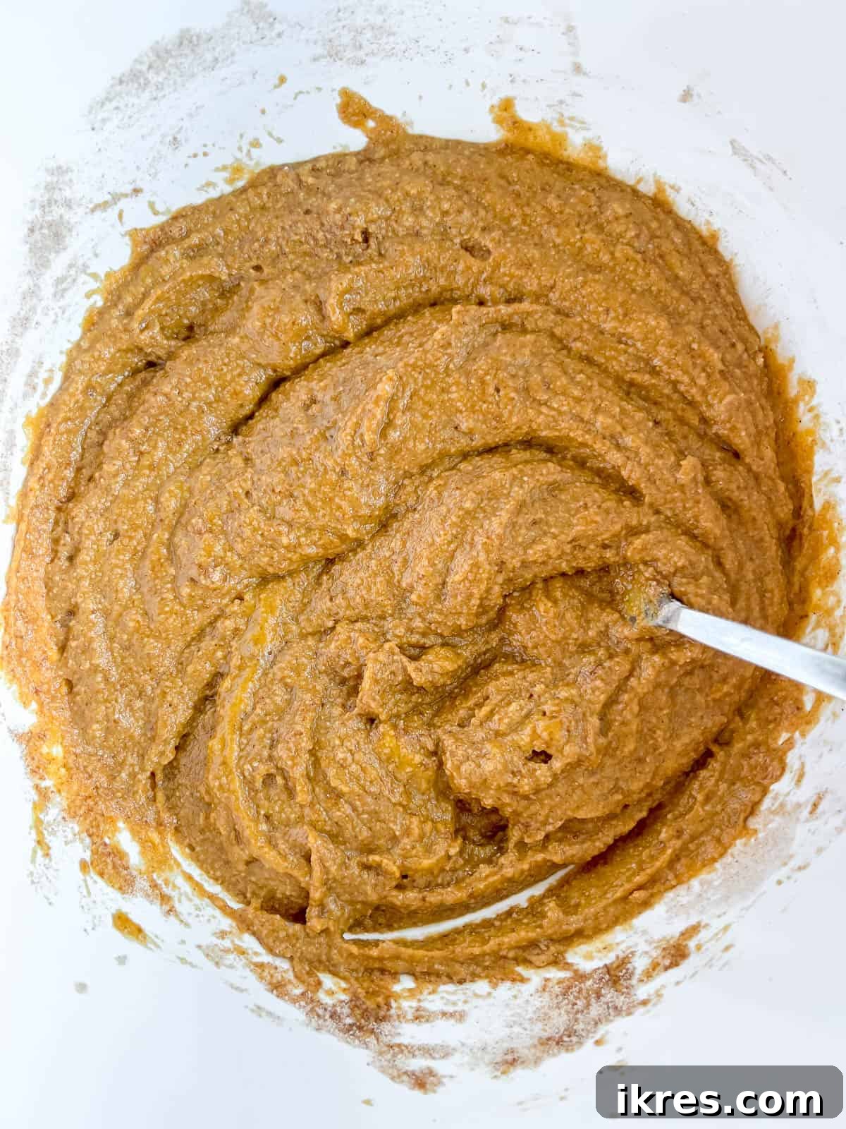 Wet and dry ingredients for pumpkin muffins mixed together in a bowl.