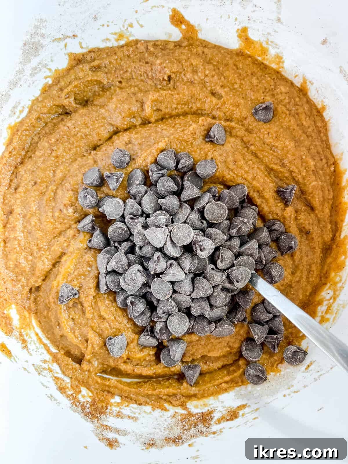 Chocolate chips added to paleo pumpkin chocolate chip muffins batter.