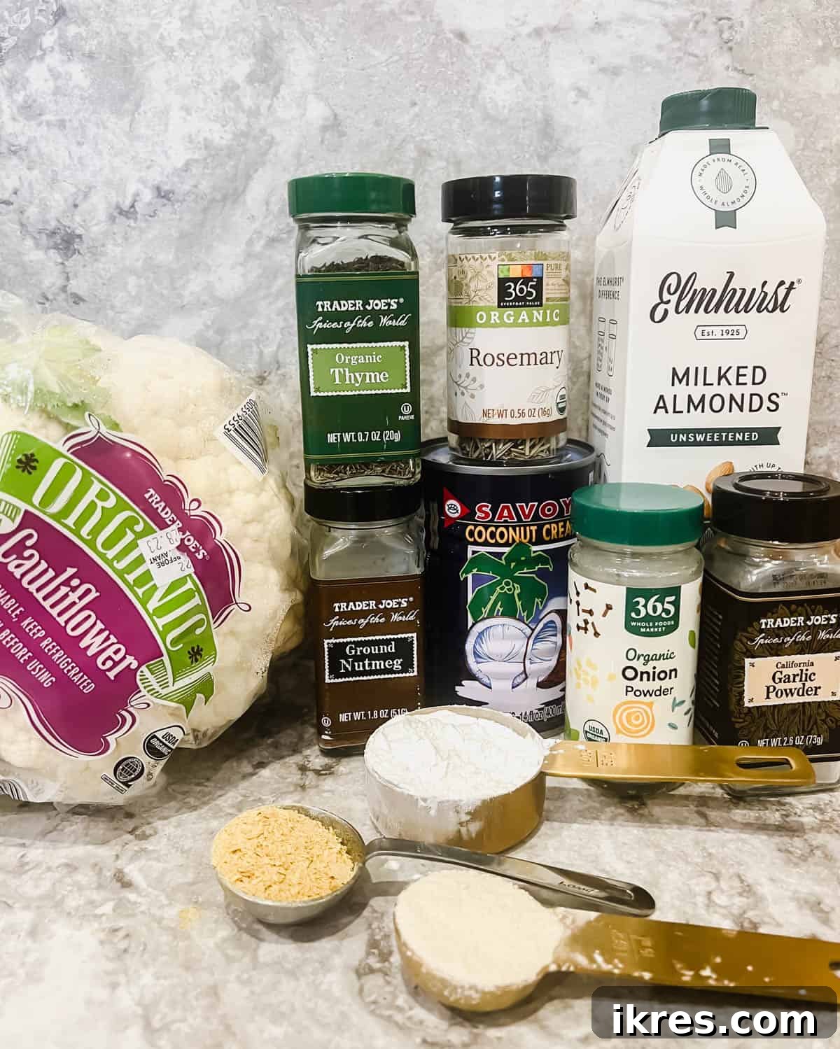 Vegan Paleo Dairy Free Cauliflower Bake 4 A flat lay of all the essential ingredients laid out on a table, including a head of cauliflower, various flours, milks, and spices, ready for making the vegan cauliflower casserole.