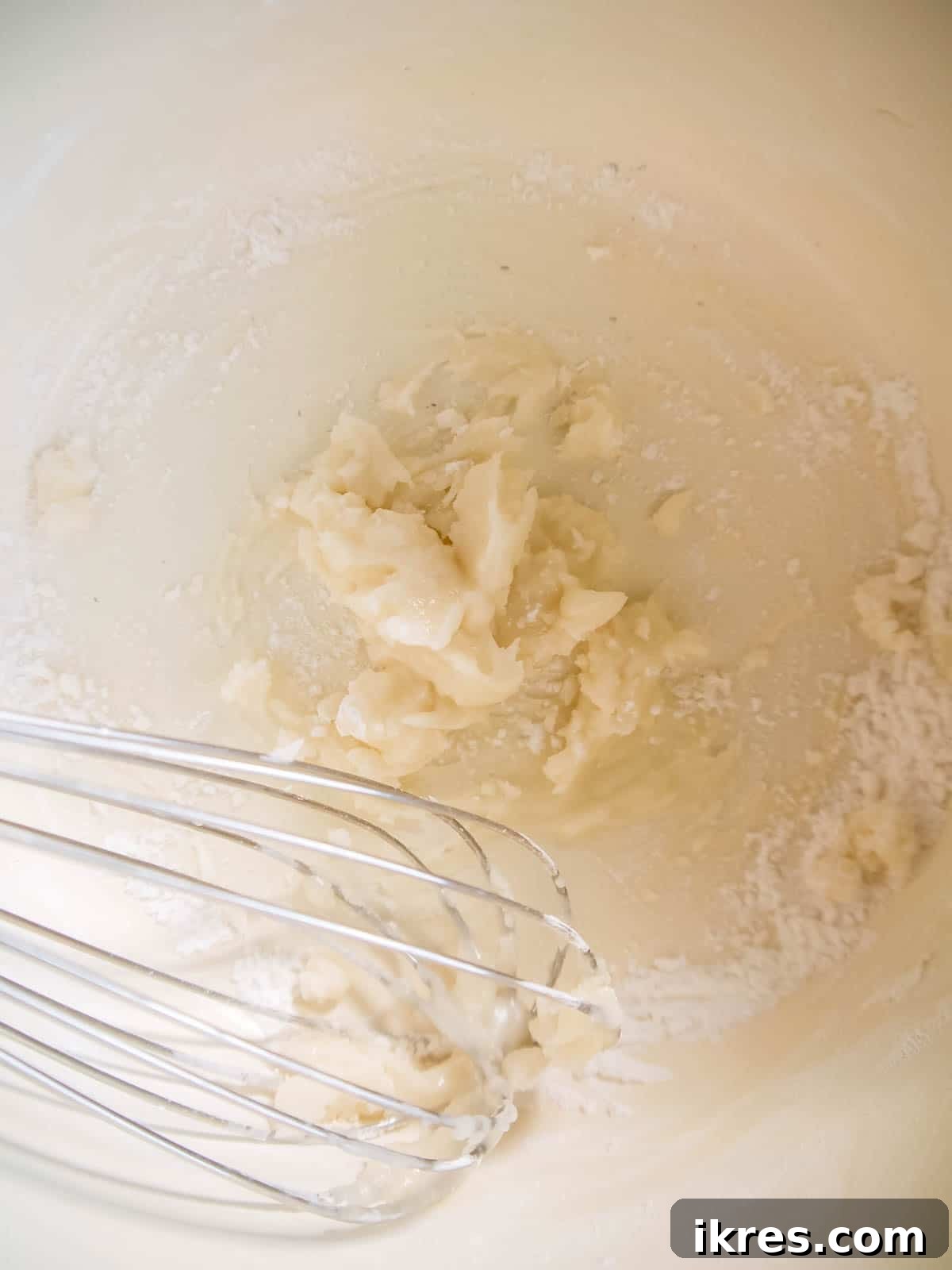 Vegan Paleo Dairy Free Cauliflower Bake 6 A pan on a stovetop with olive oil, tapioca flour, and coconut flour being whisked together to form the base of the creamy vegan sauce.