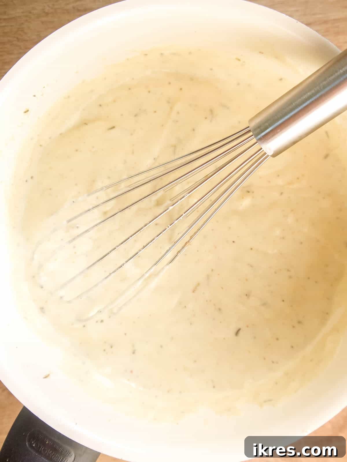 Vegan Paleo Dairy Free Cauliflower Bake 7 More ingredients, including coconut cream and almond milk, being whisked into the flour mixture in the pan to create the smooth vegan sauce.