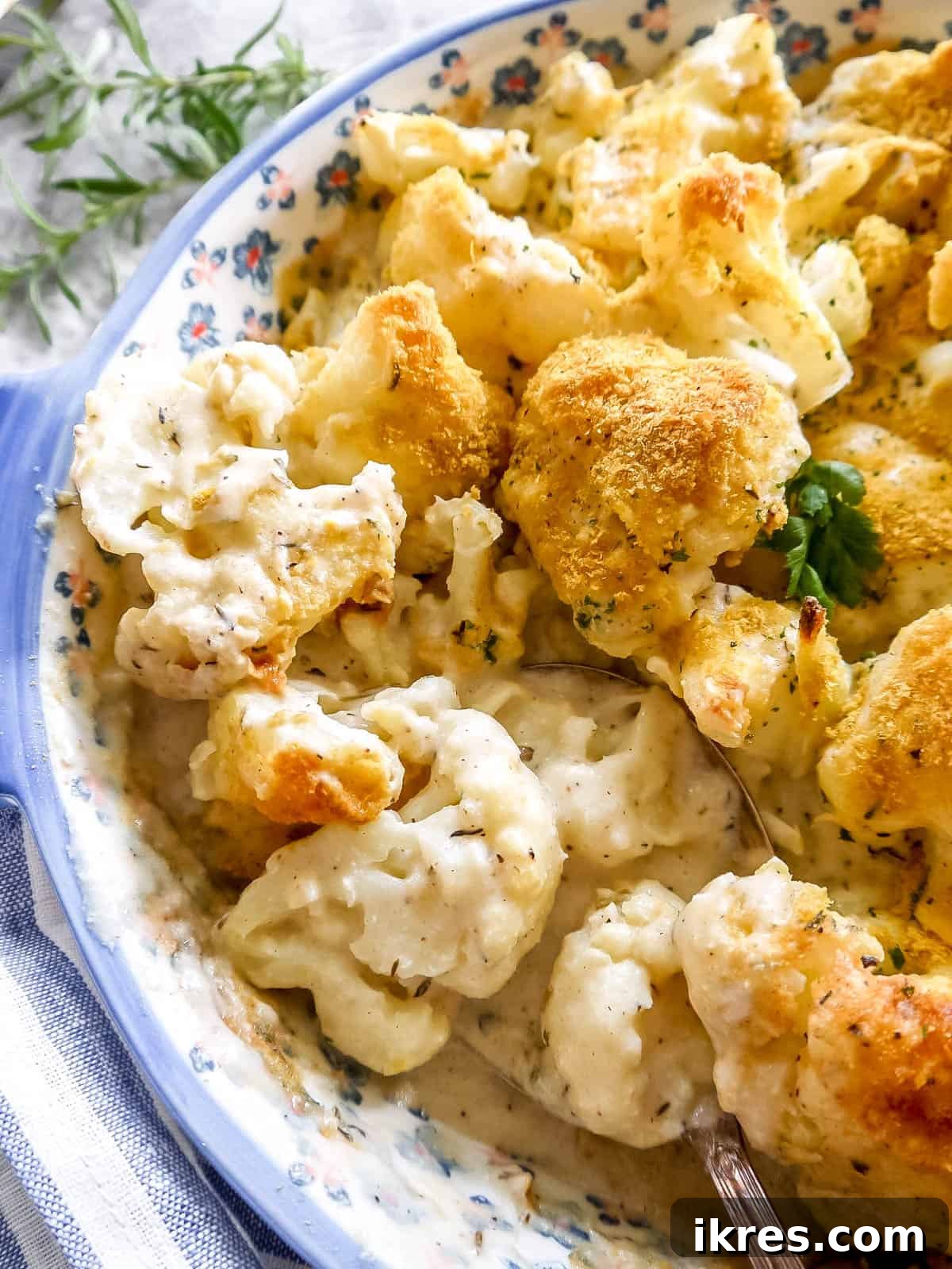 Vegan Paleo Dairy Free Cauliflower Bake 10 A dairy-free cauliflower bake, still in the dish, with a serving spoon removing a portion, showing its creamy interior and golden crust.