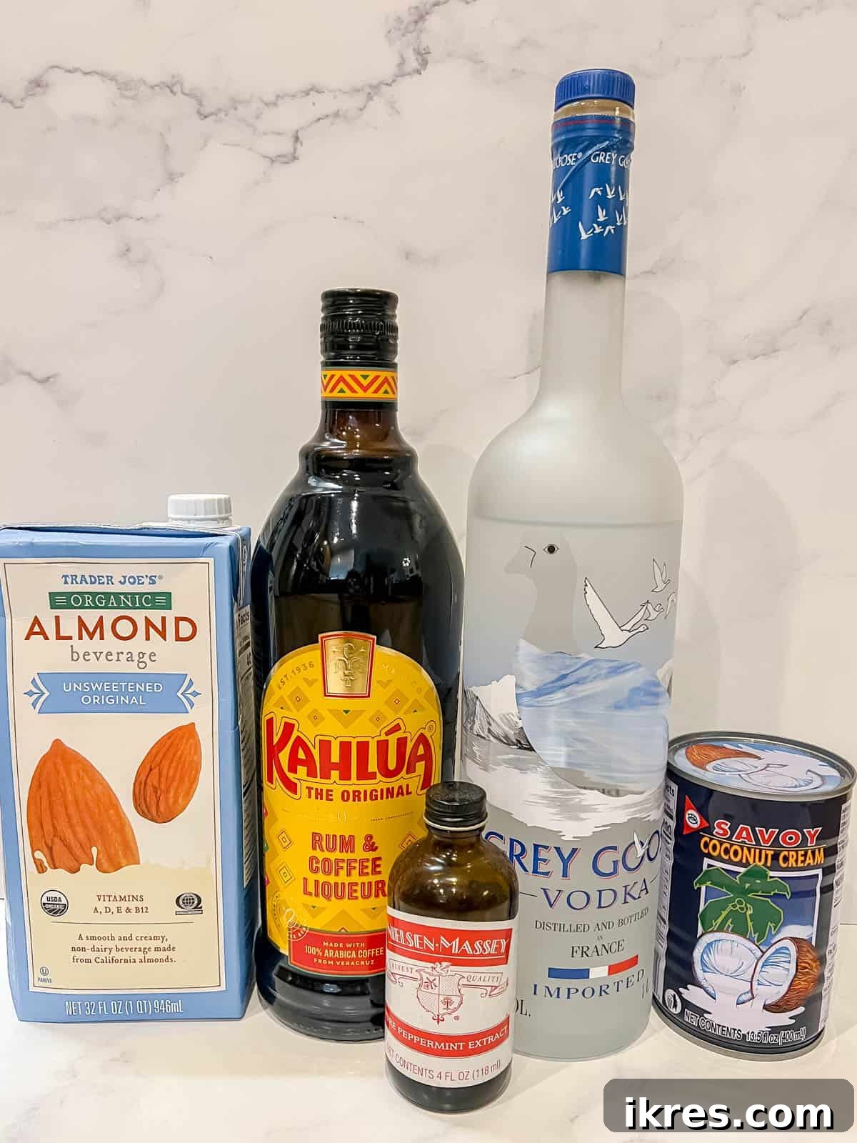 Frosted Peppermint White Russian 3 Assorted ingredients for a peppermint dairy-free white russian cocktail, including almond milk, coconut cream, vodka, coffee liqueur, and peppermint extract.