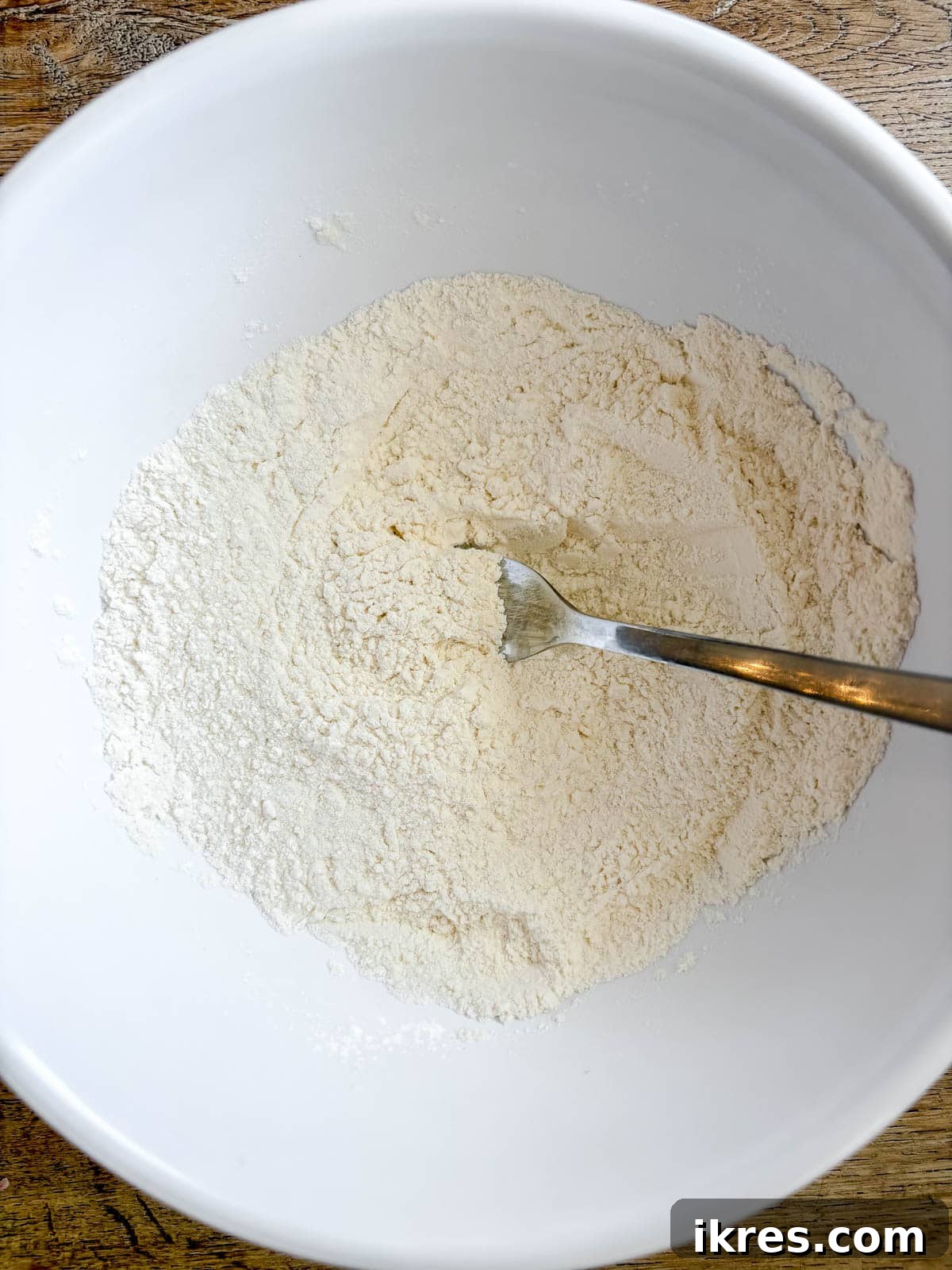 Naturally Dairy-Free Olive Oil Blueberry Muffins 4 Dry ingredients (flour, salt, baking powder) mixed in a glass bowl.