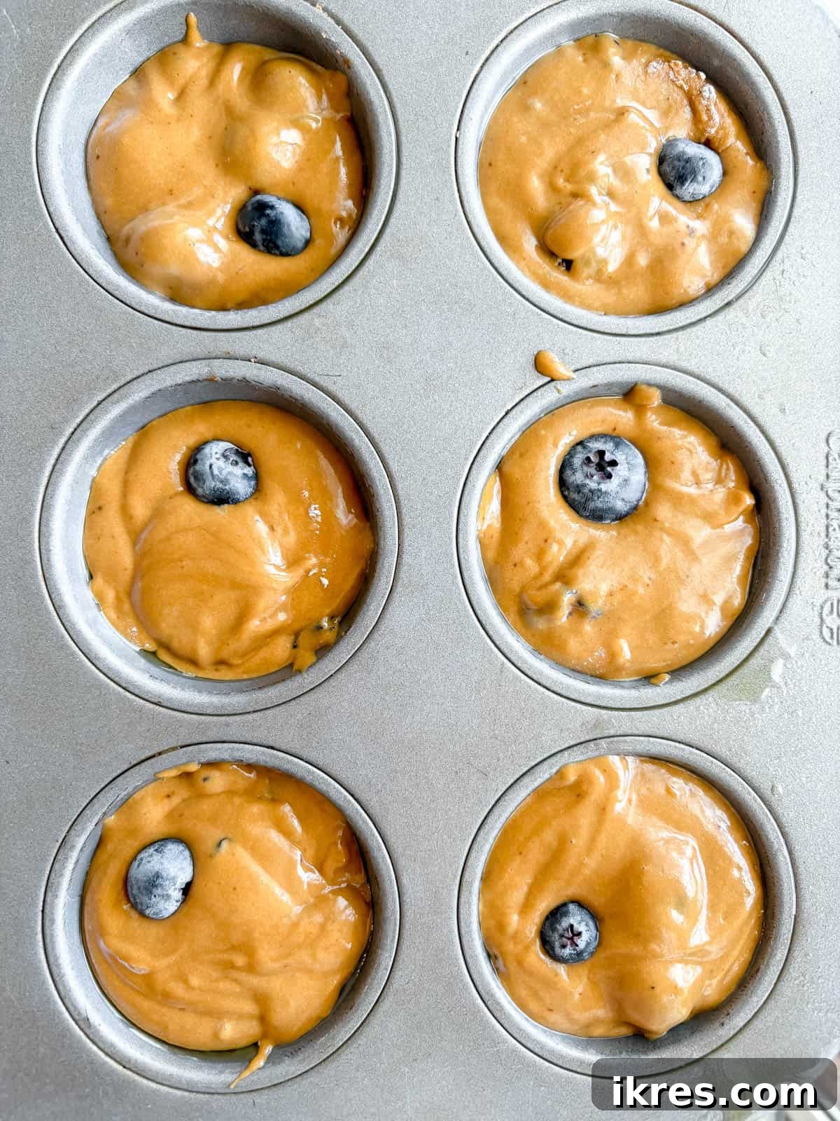 Naturally Dairy-Free Olive Oil Blueberry Muffins 9 Muffin batter scooped into a lined muffin tin, ready for baking.