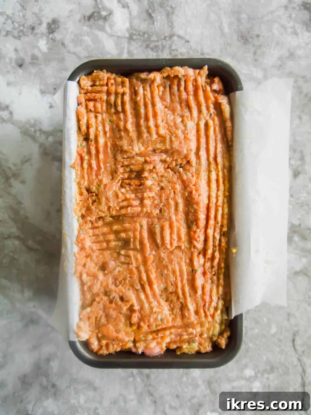 Meatloaf mixture shaped in a loaf tin before applying the sauce.