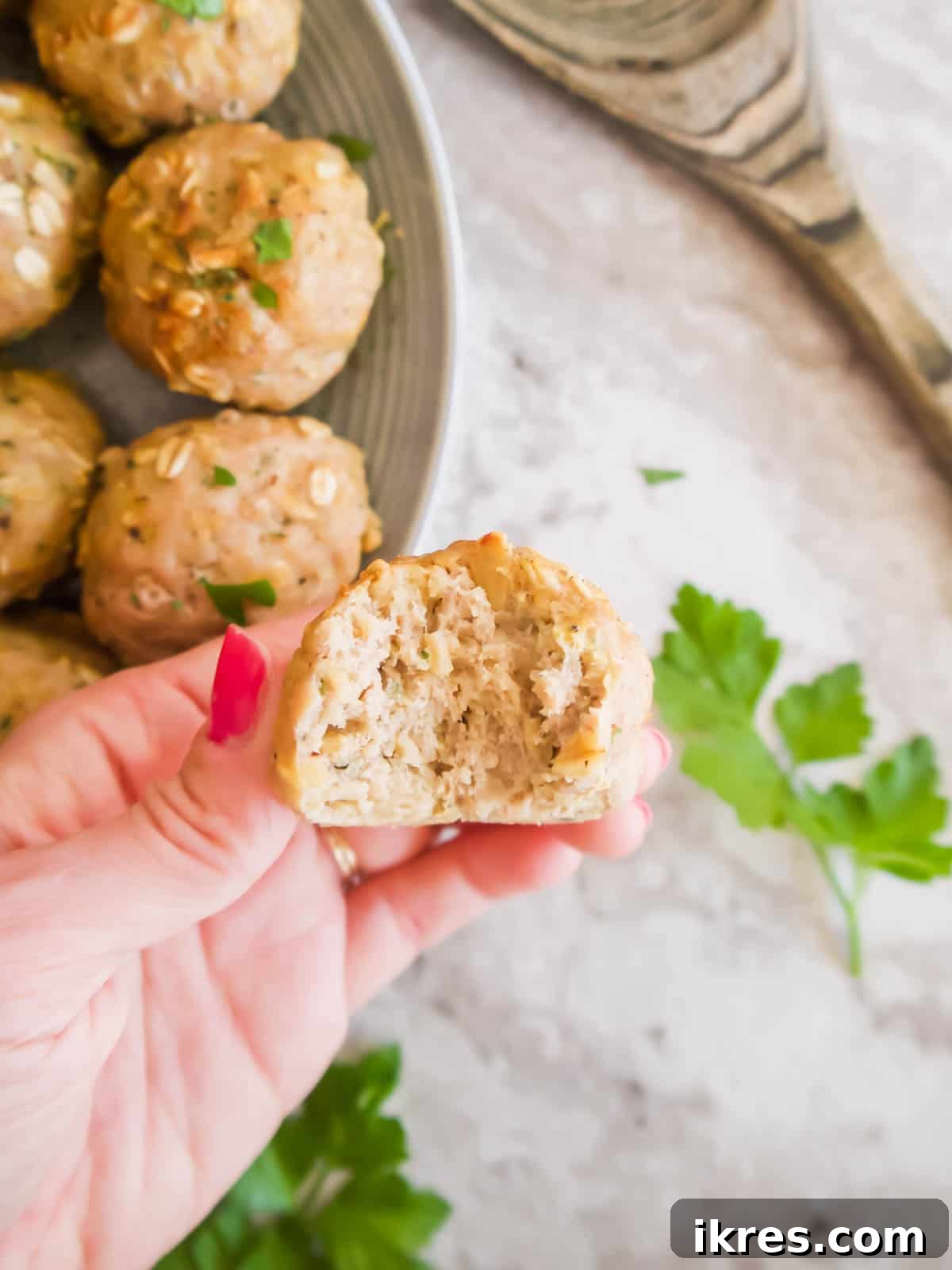 Gluten Free Dairy Free Turkey Meatballs with Oats 4 A close-up shot of a healthy ground turkey meatball with a bite taken out, revealing its juicy interior.