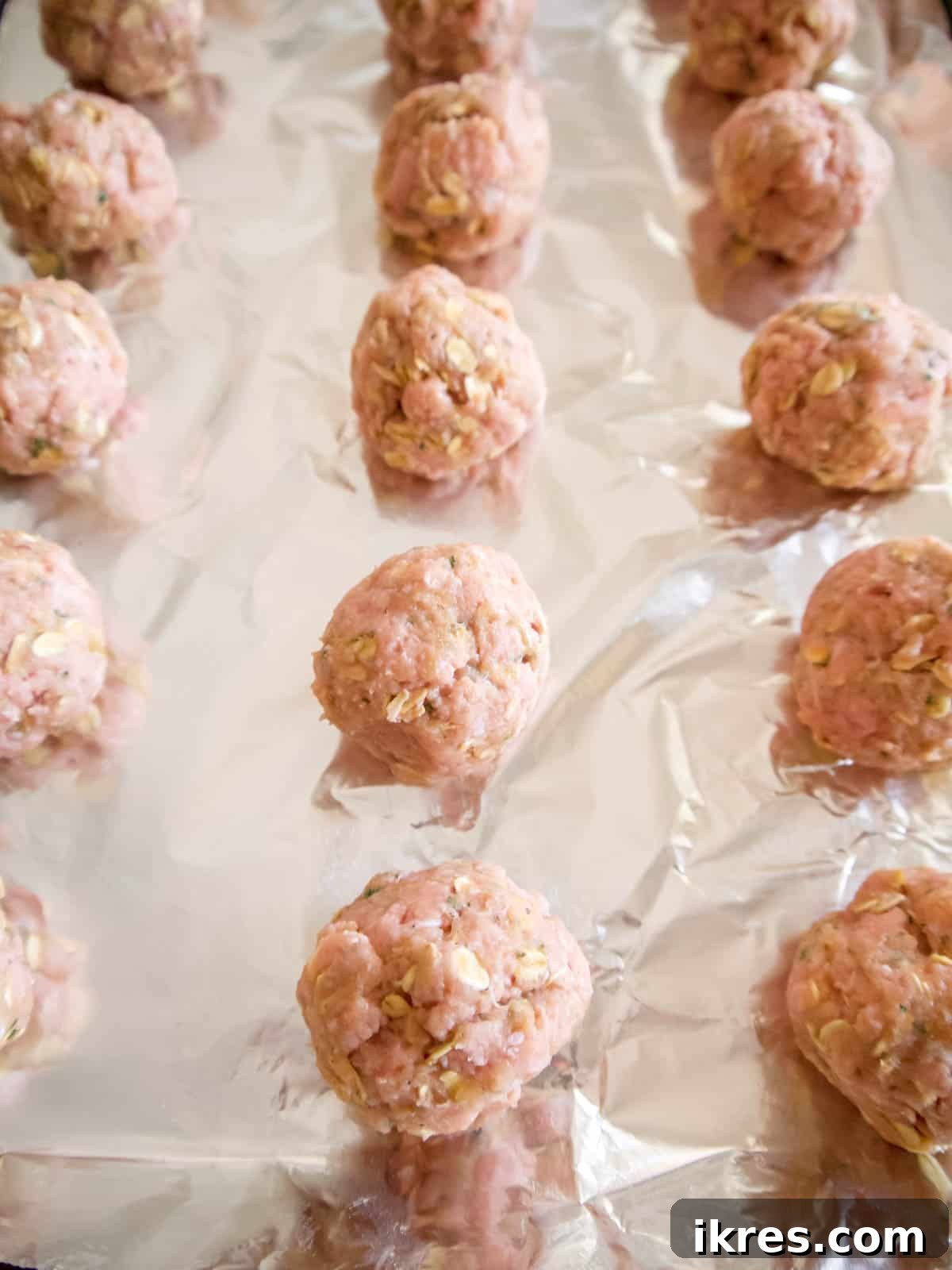 Gluten Free Dairy Free Turkey Meatballs with Oats 7 Raw meatballs, perfectly rolled into balls, neatly arranged on a lined cookie sheet, ready for baking.