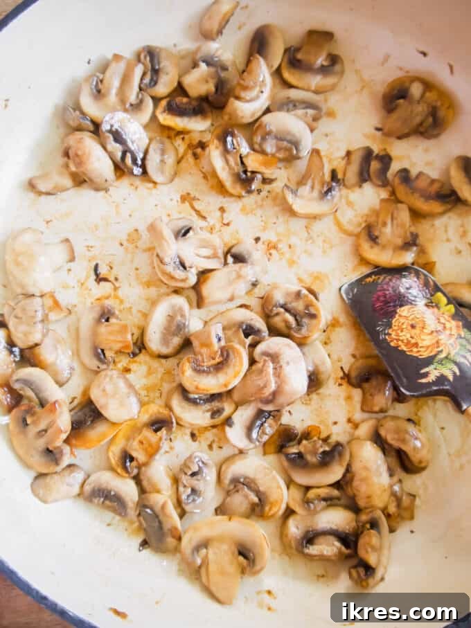 Sliced mushrooms sautéing in olive oil in a hot pan until golden brown.