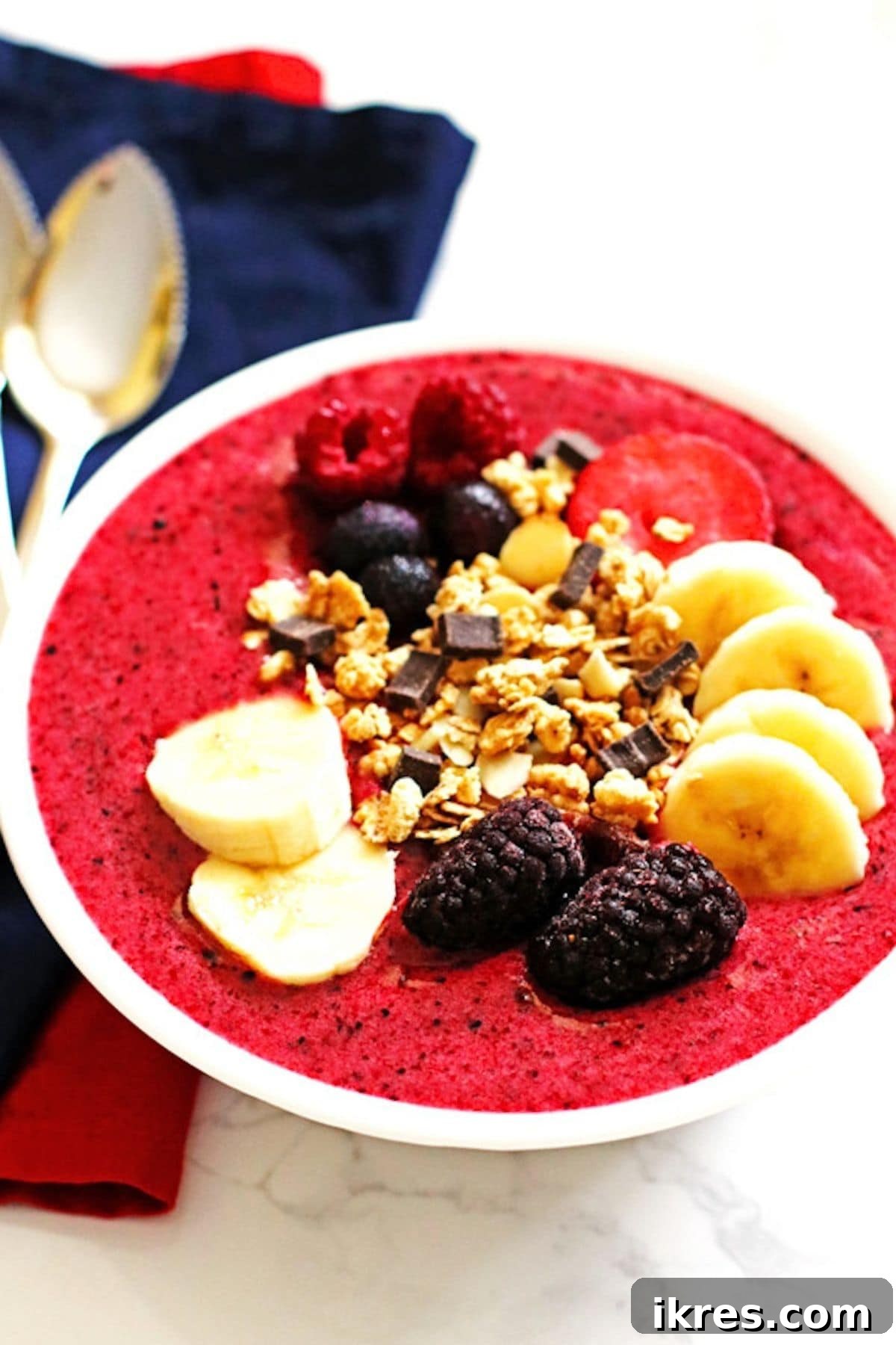 Berry Banana Bliss Bowl 2 A vibrant pink Berry Banana Smoothie Bowl, garnished beautifully with fresh berries, banana slices, and a sprinkle of granola, sits on a rustic wooden surface, highlighting a healthy and delicious breakfast option.