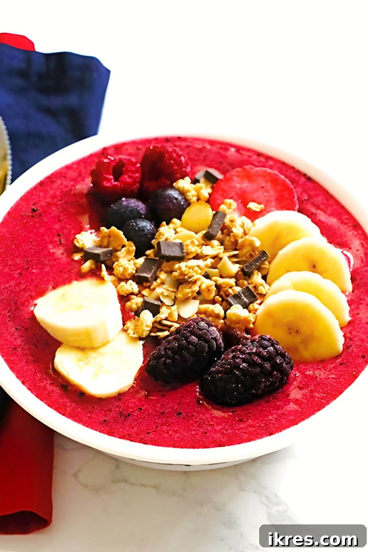 Berry Banana Bliss Bowl 3 A beautifully prepared Berry Banana Smoothie Bowl, topped with an artful arrangement of banana slices, whole fresh berries, and crunchy granola, ready to be enjoyed as a healthy and refreshing meal.